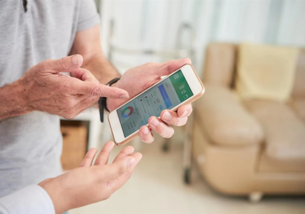 Patient using a mobile health application under clinician guidance, illustrating remote monitoring, patient engagement and data sharing in digital care pathways.