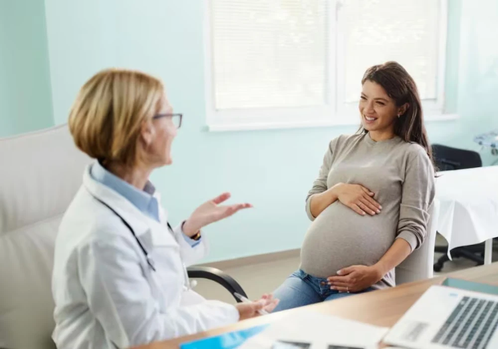 A prenatal consultation in a clinical setting, with a pregnant woman speaking with a clinician.