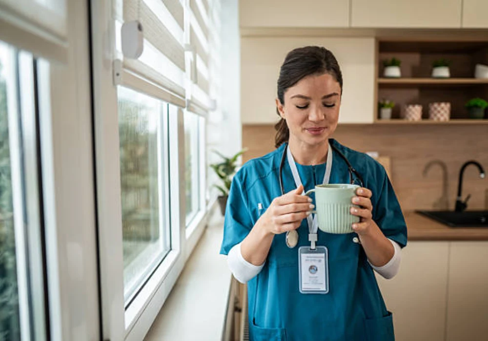 Healthcare professional in scrubs taking a brief break with a cup of coffee, illustrating staff wellbeing, workload balance and everyday life in clinical practice.