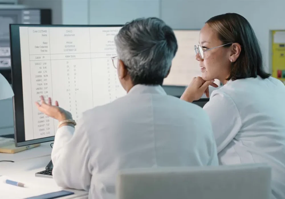 Clinicians reviewing diagnostic data on a computer screen, supporting laboratory reporting, clinical analysis and healthcare decision-making.
