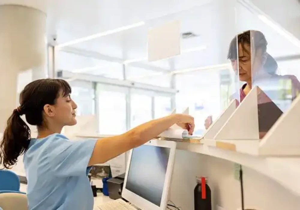 Nurse handling documents at hospital reception, supporting patient administration, clinical records management and healthcare workflow coordination.
