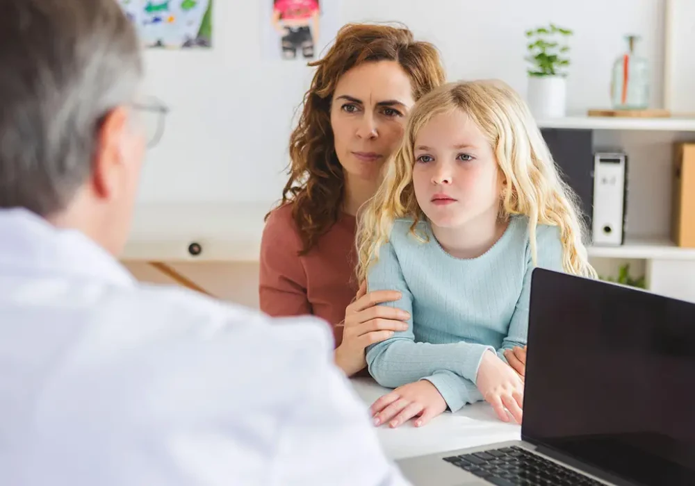 Paediatric consultation with doctor, mother and child, supporting family-centred care, child health assessment and clinical decision-making.