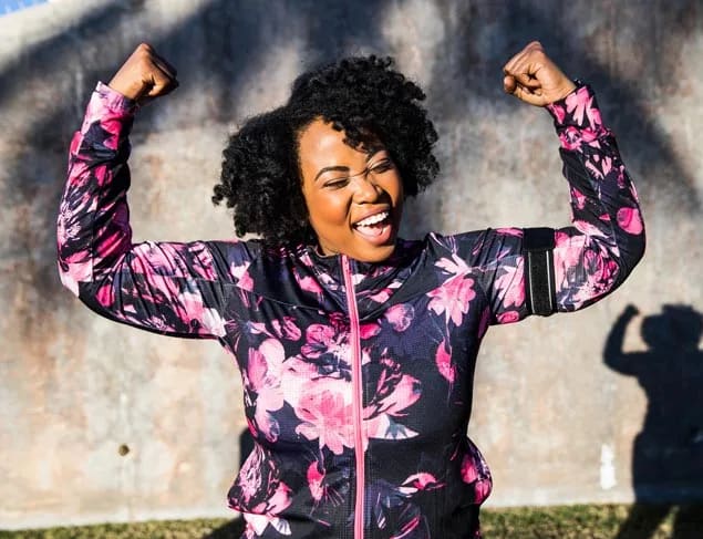 Happy woman doing a strong arm pose after an outdoor workout