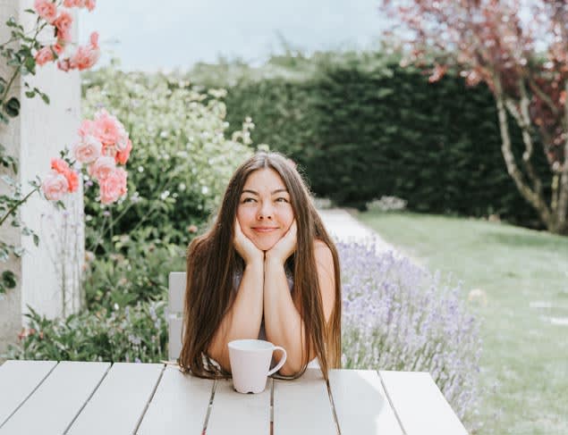 Relaxed young woman enjoying a cup of tea in the rose garden