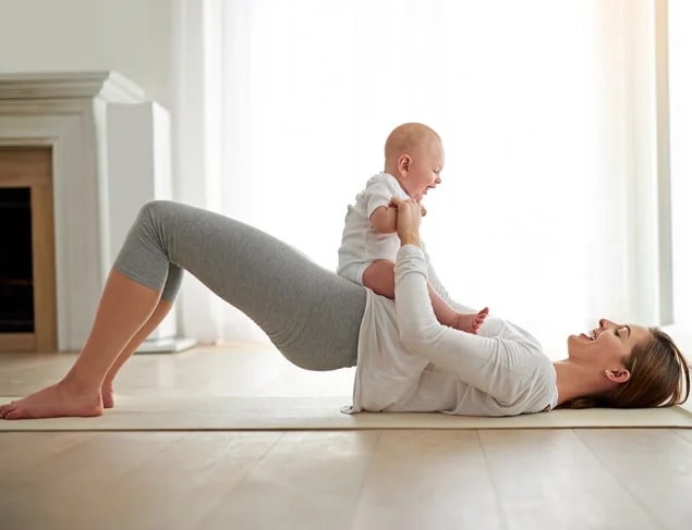 Mum in bridge pose with her happy baby on her belly