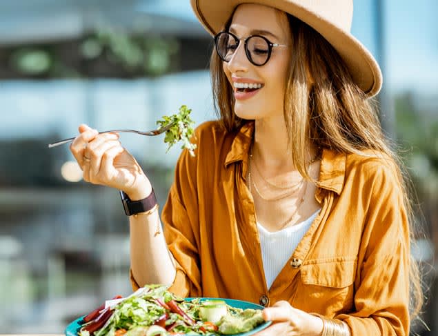 Young woman enjoying a plate of salad at an outdoor cafe