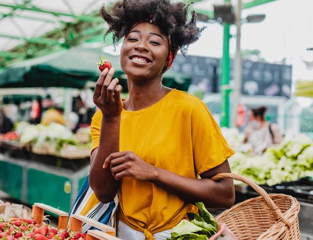 Happy woman shopping for strawberries at the local farmer's market