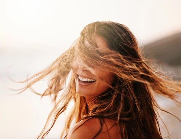 Carefree woman laughing and swinging her hair around at the beach