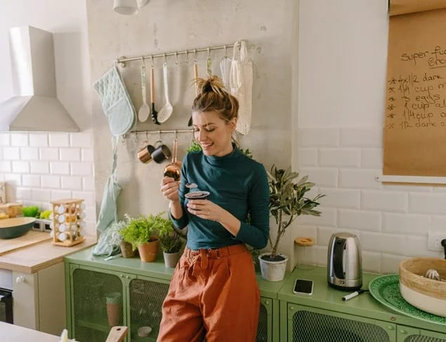 Young smiling blonde woman having healthy snack in her kitchen