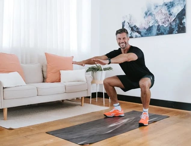 Personal Trainer Sam Wood doing a squat exercise indoors