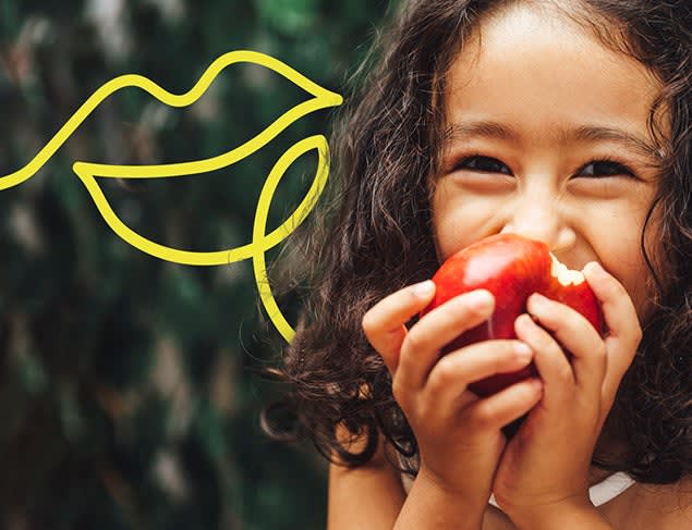 Happy girl smiling and eating a red apple