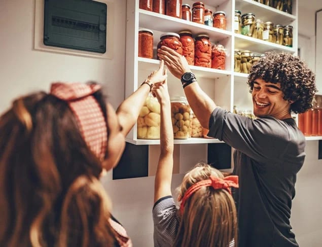 A happy family takes jars with pickled vegetables from the pantry shelf.