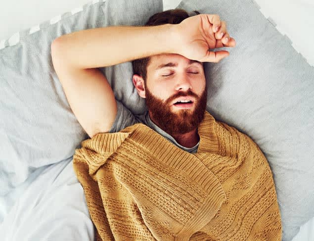 Young man asleep with his mouth slightly opening and his hand resting on his forehead