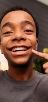 Photo of young man pointing to his smile