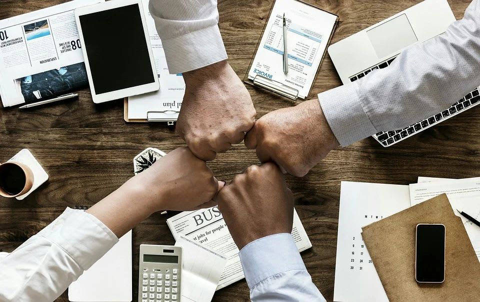 Four people fist bumping over a desk