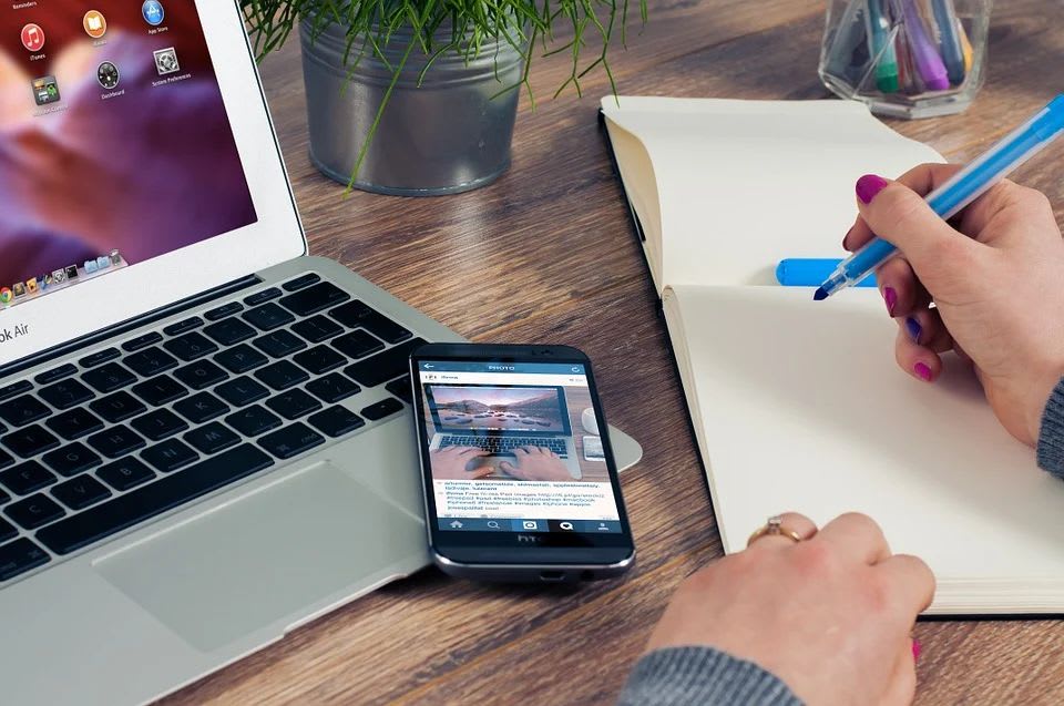 Person using computer, phone, and notebook