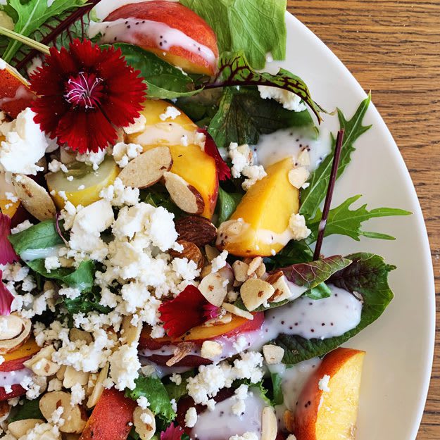 Salad Philosophy: Close up of delicious salad: arugula, mizuna, peaches, sorrel, goat cheese