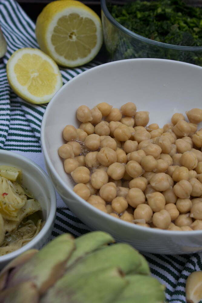 Close up of fresh ingredients | Garbanzo beans, marinated artichoke hearts, spinach, and lemon