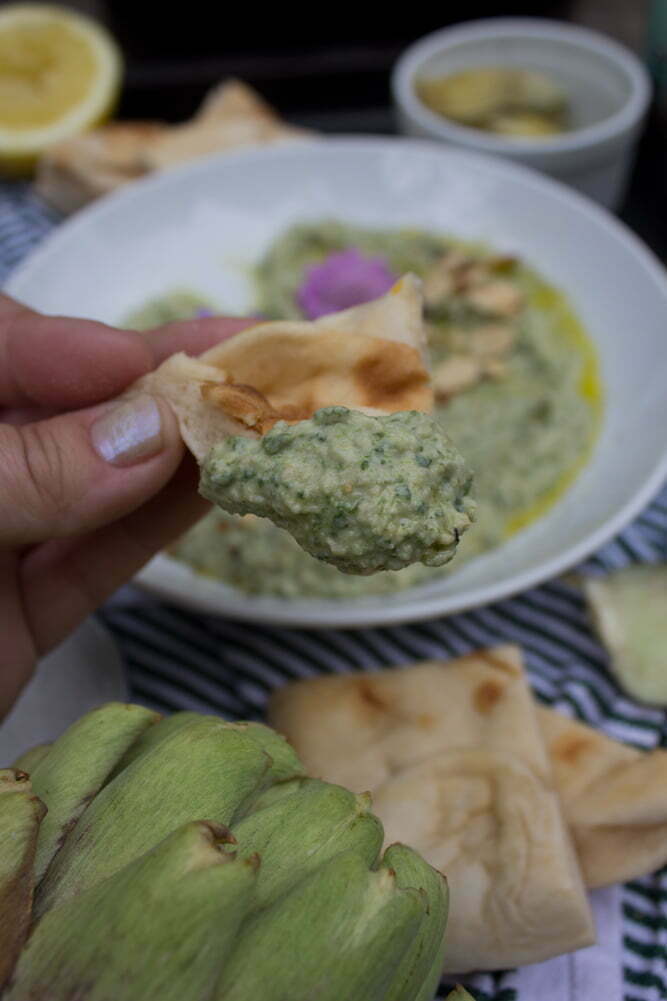 SpinachArtichokeHummus_39web Closeup | Hand holding small piece of flatbread with Spinach Artichoke Hummus