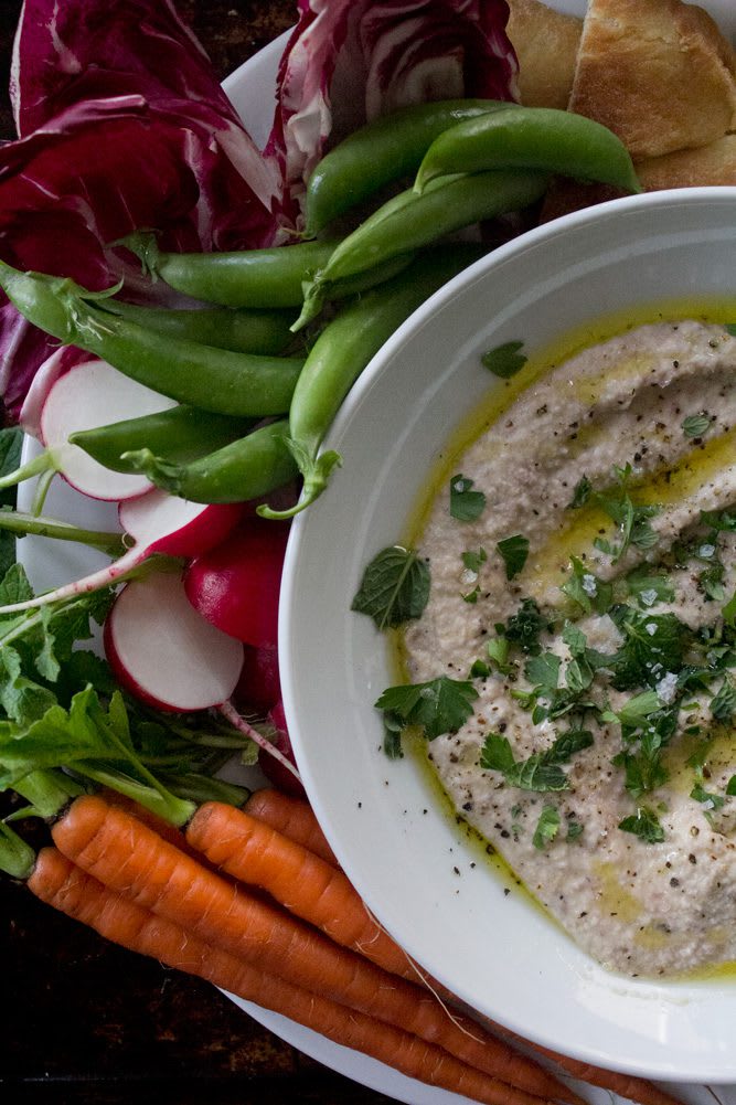 Roasted Radish hummus plated with fresh carrots, sweet peas, fresh radishes, raddichio and flatbread