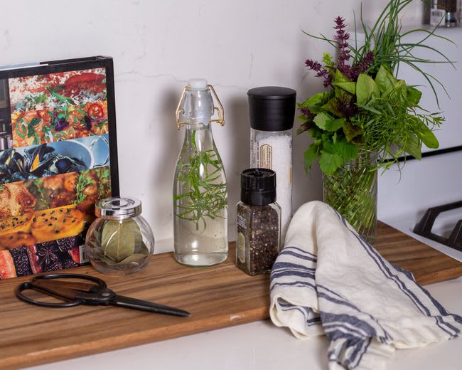 Kitchen Counter with Tarragon Vinegar, spices, and garden scissors on a cutting board