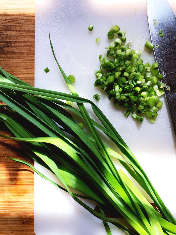 Whole green onion scapes and some diced on cutting board