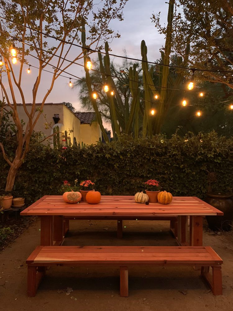 HP_SG_DiningTable_Evening_web Heirloom Potager Showcase Garden Outdoor Dining Room at night with overhead outdoor string lights