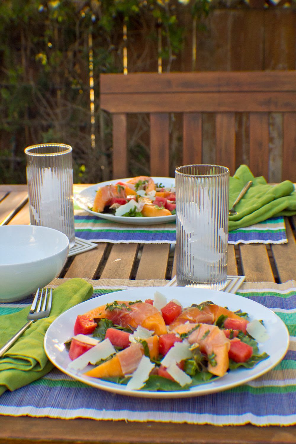 MelonProsciuttoSalad_15_web Two meal settings at outdoor table with Melon + Nectarine Prosciutto Summer Salad