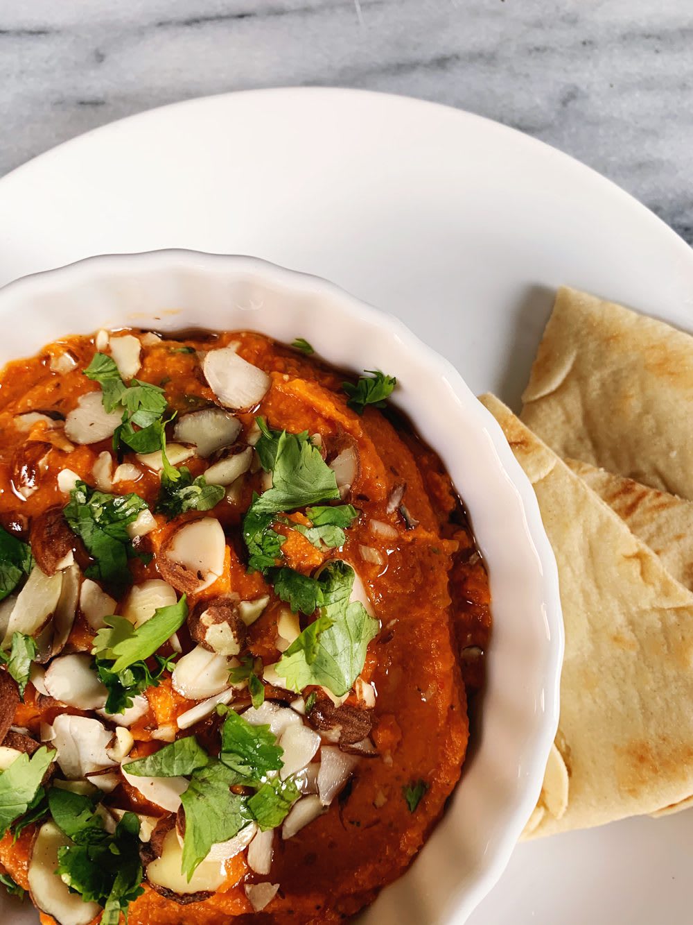 RoastedRedPepperHummus_web2 Close up of Roasted Red Pepper Hummus with Harissa, sliced almonds, and cilantro