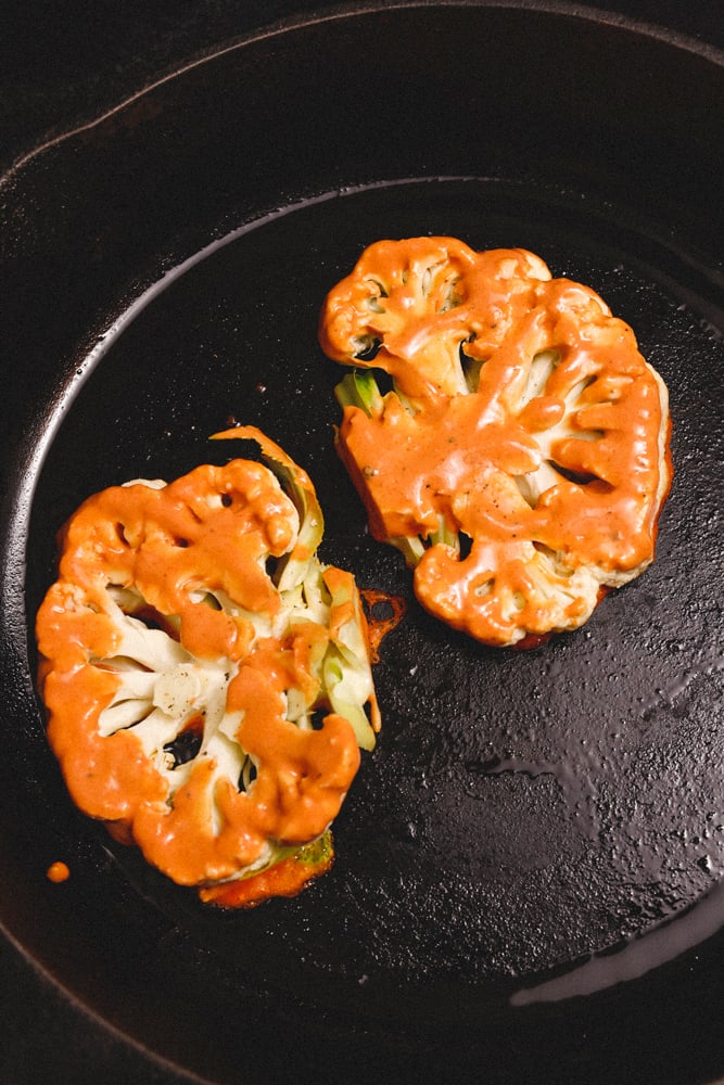 SpicyCauliflowerSteaks_GreenGoddessHummus_w3 Spicy Cauliflower steaks cooking in cast iron pan.