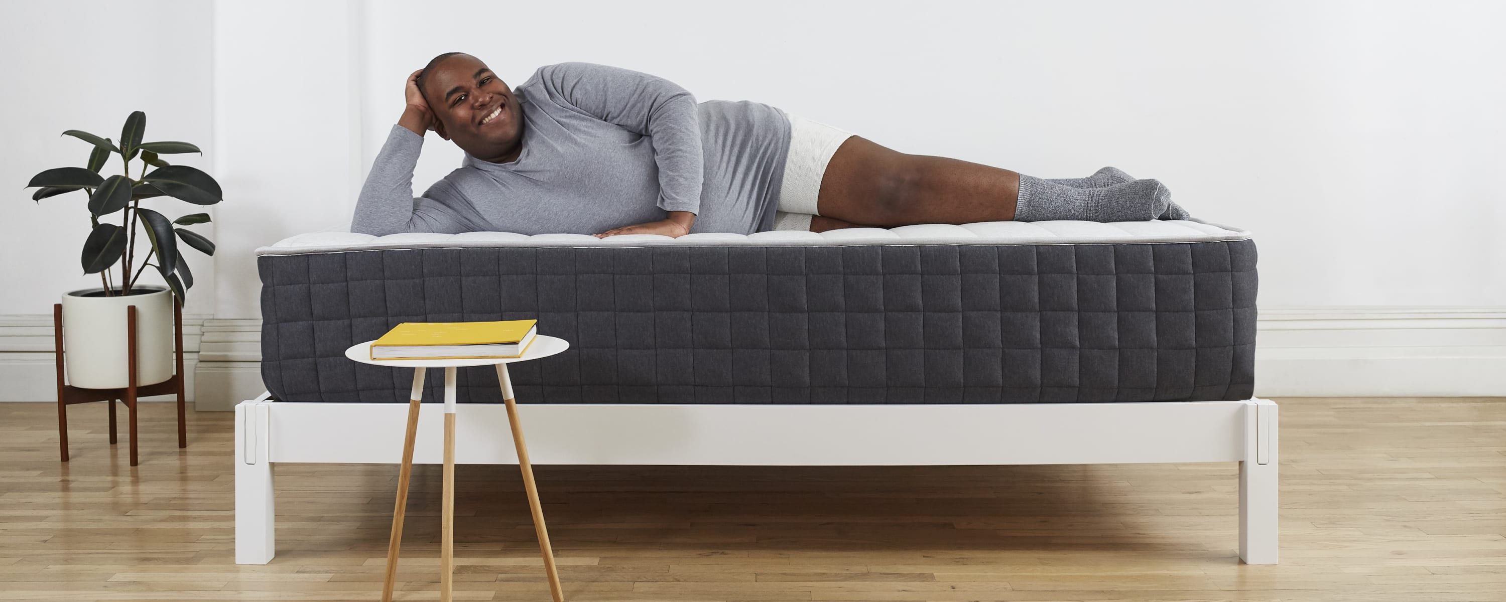 Man laying on Helix Plus mattress with side table