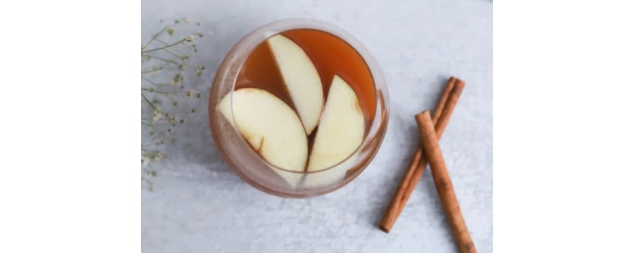 Hot toddy with apple slices and cinnamon sticks