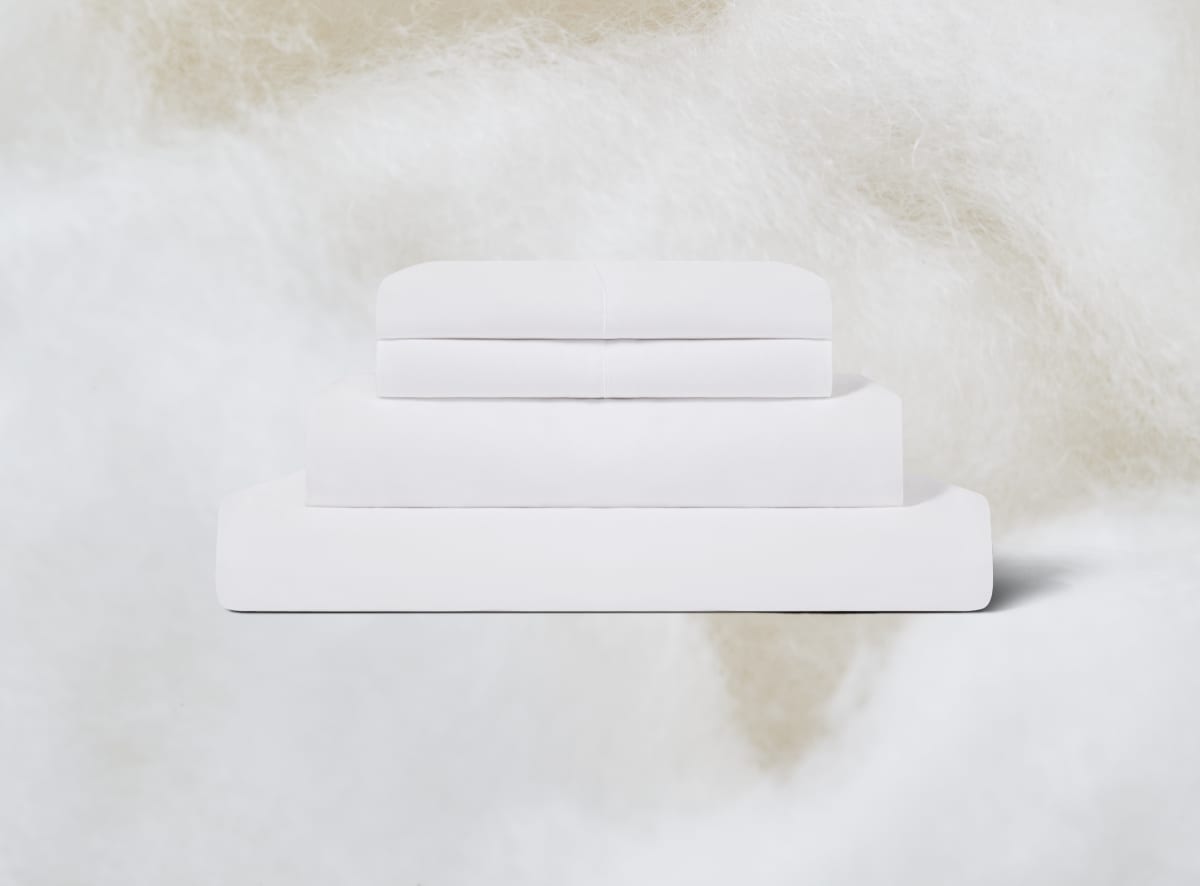 The White Sheet Set folded on top of a cotton background