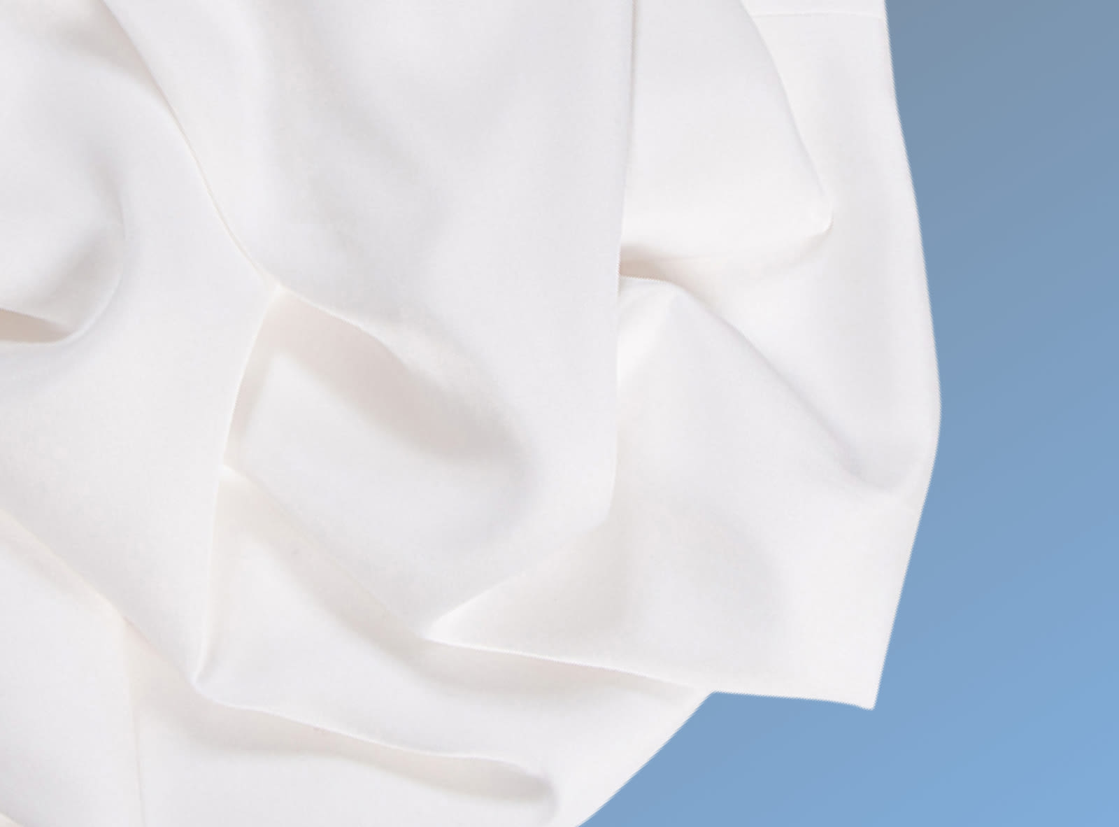 White cotton blend sheets crumpled on a blue background