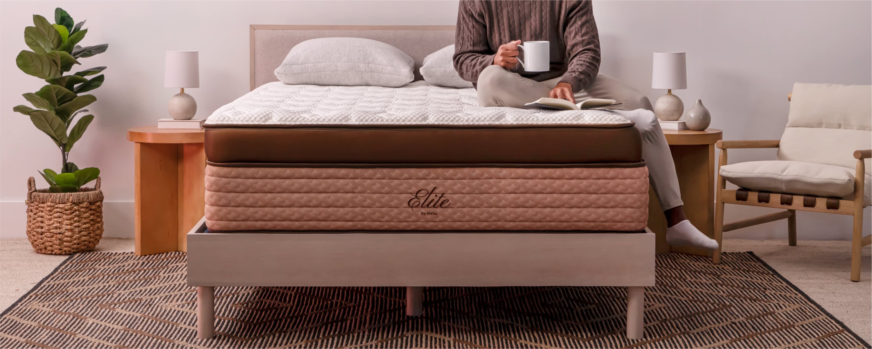 Person sitting on Helix Elite mattress holding a white mug