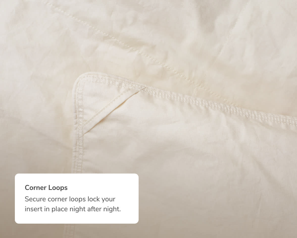 A closeup image of the Natural Down Duvet Insert with a callout to its secure corner loops