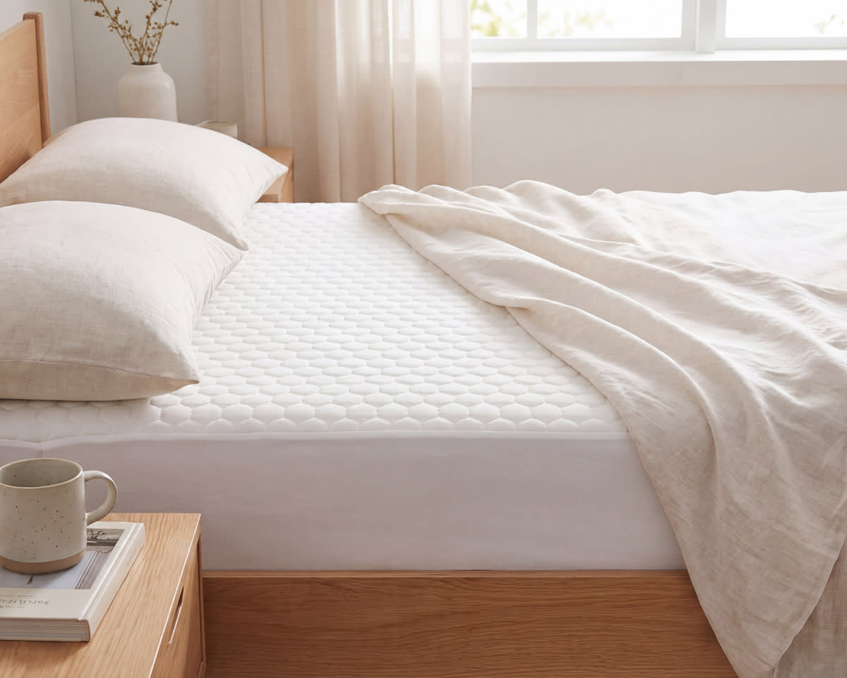 An image of the GlacioTex Cooling Mattress Protector on a bed in a bedroom scene