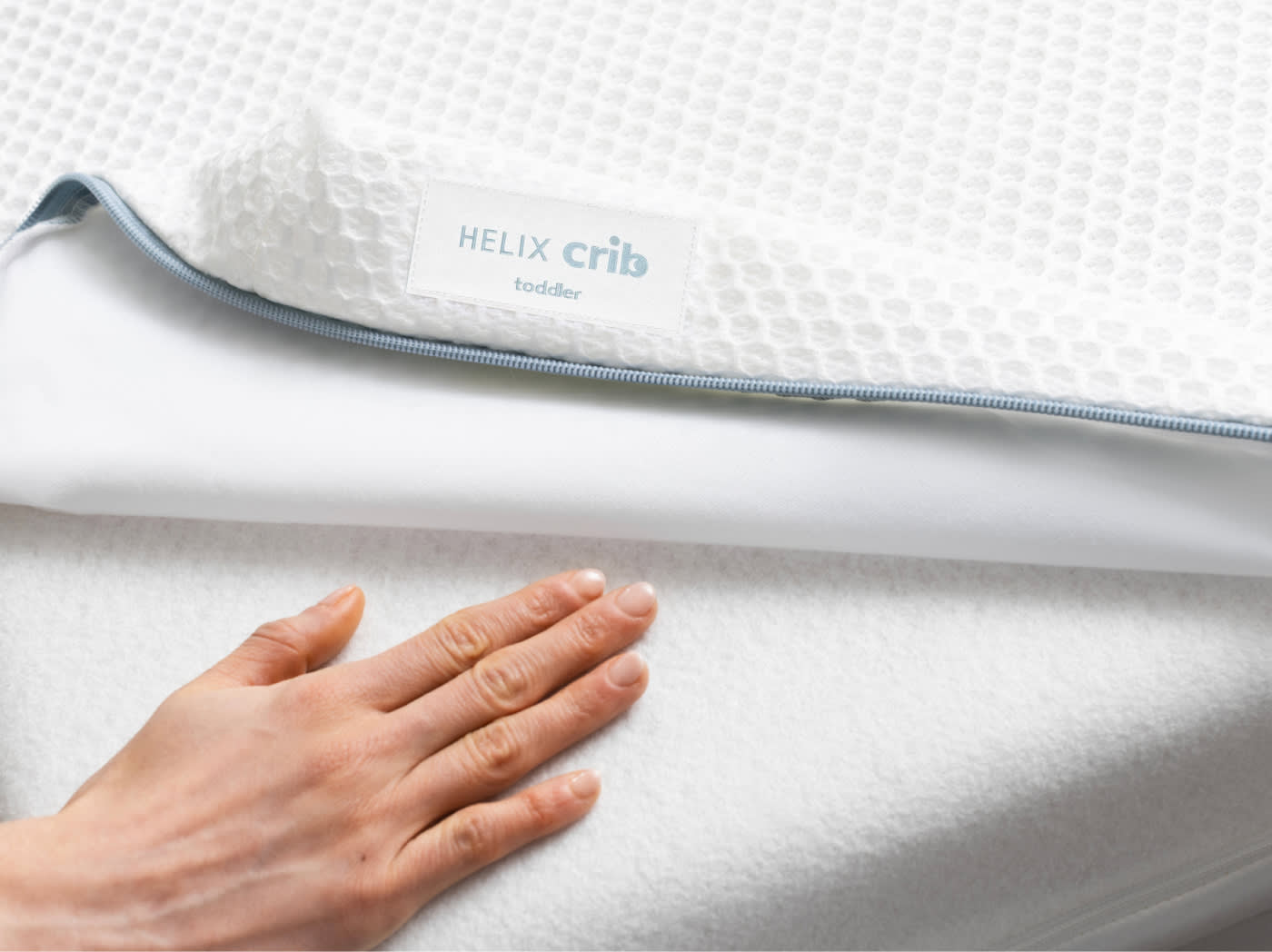 An image of the Crib Mattress Cover pulled back to show a dry crib mattress core