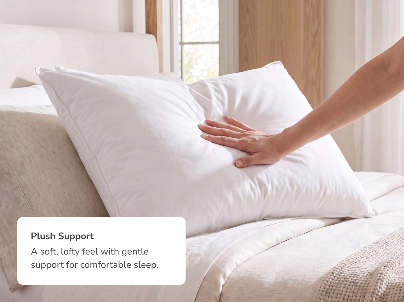 A hand pressing into the Down and Feather pillow with a callout its plush support
