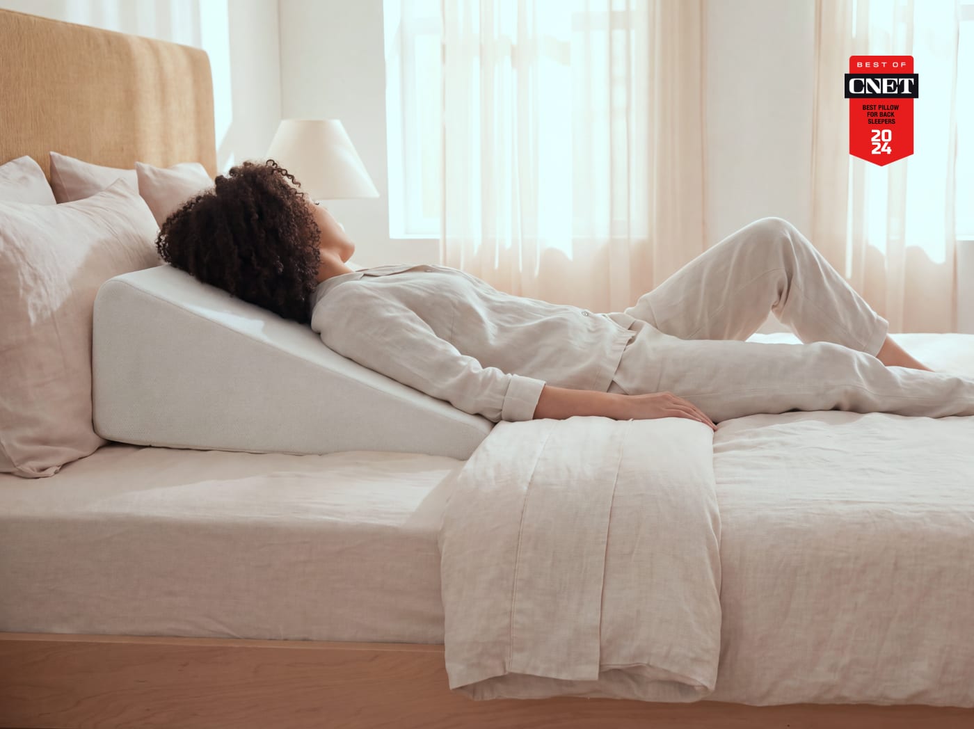 An image of a woman lying on the Wedge Pillow with a CNET award badge