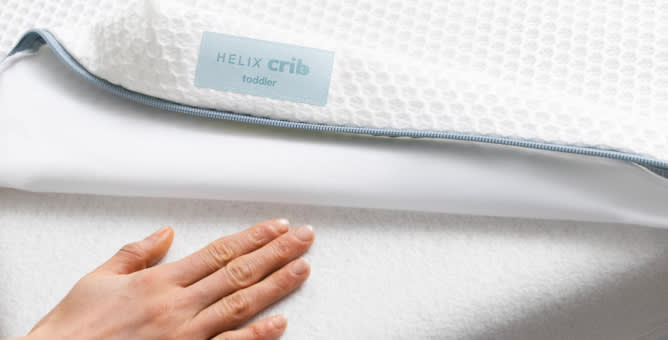An image of the Helix Crib cover with a hand placed on the bottom