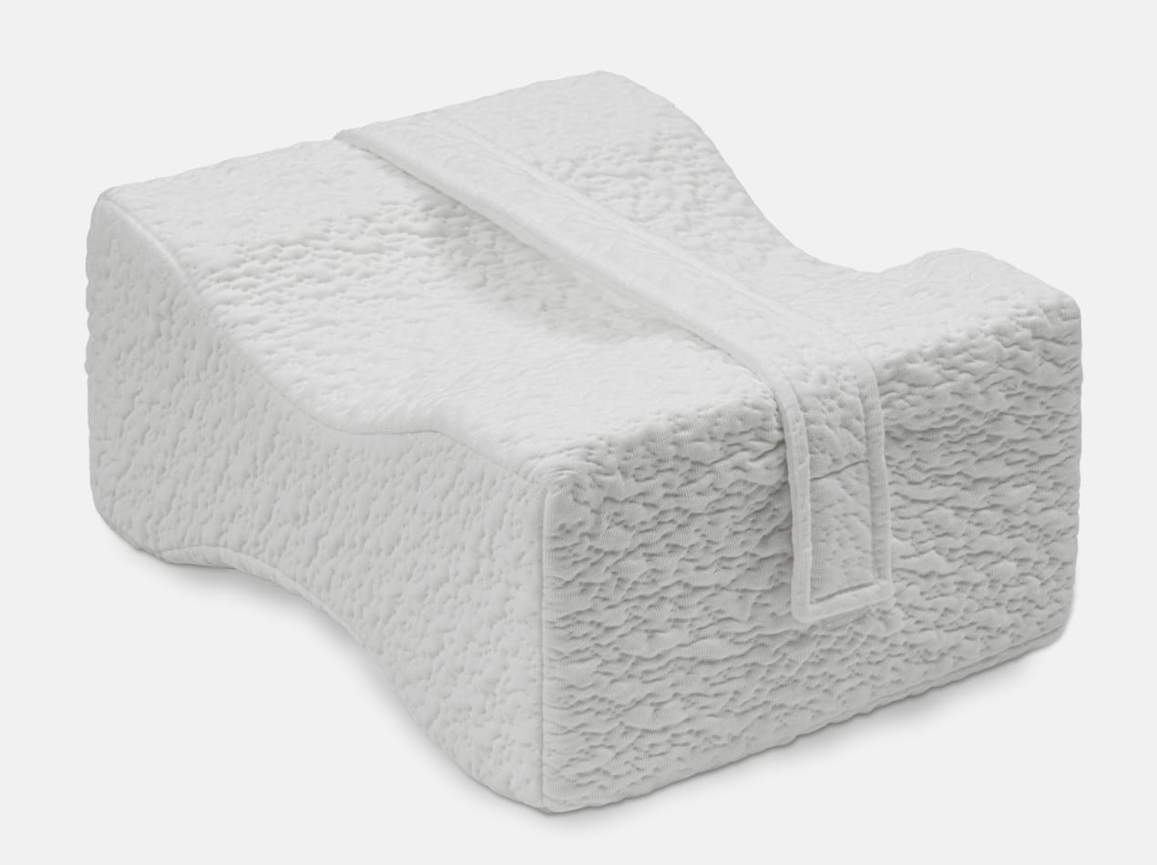 A clean, detailed shot of a white, contoured ergonomic knee pillow with an adjustable strap.