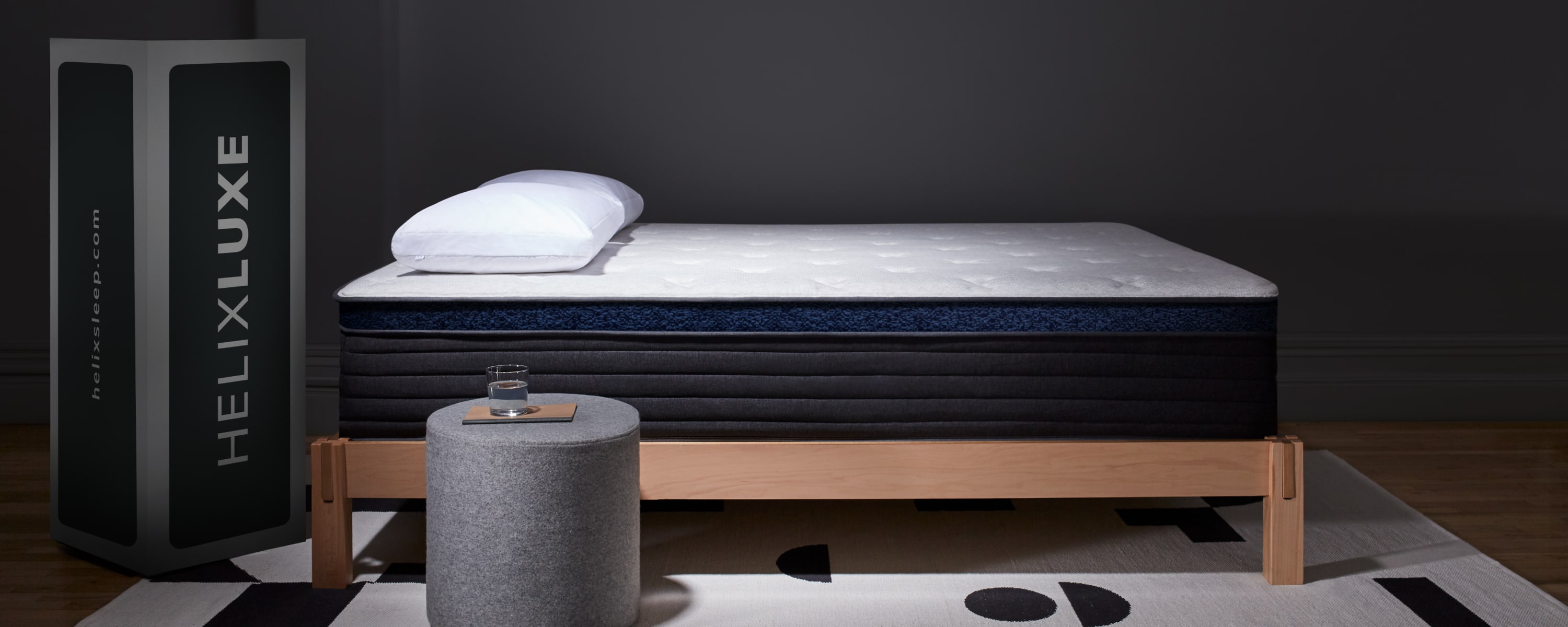 Helix Luxe Midnight mattress with side table with a glass of water