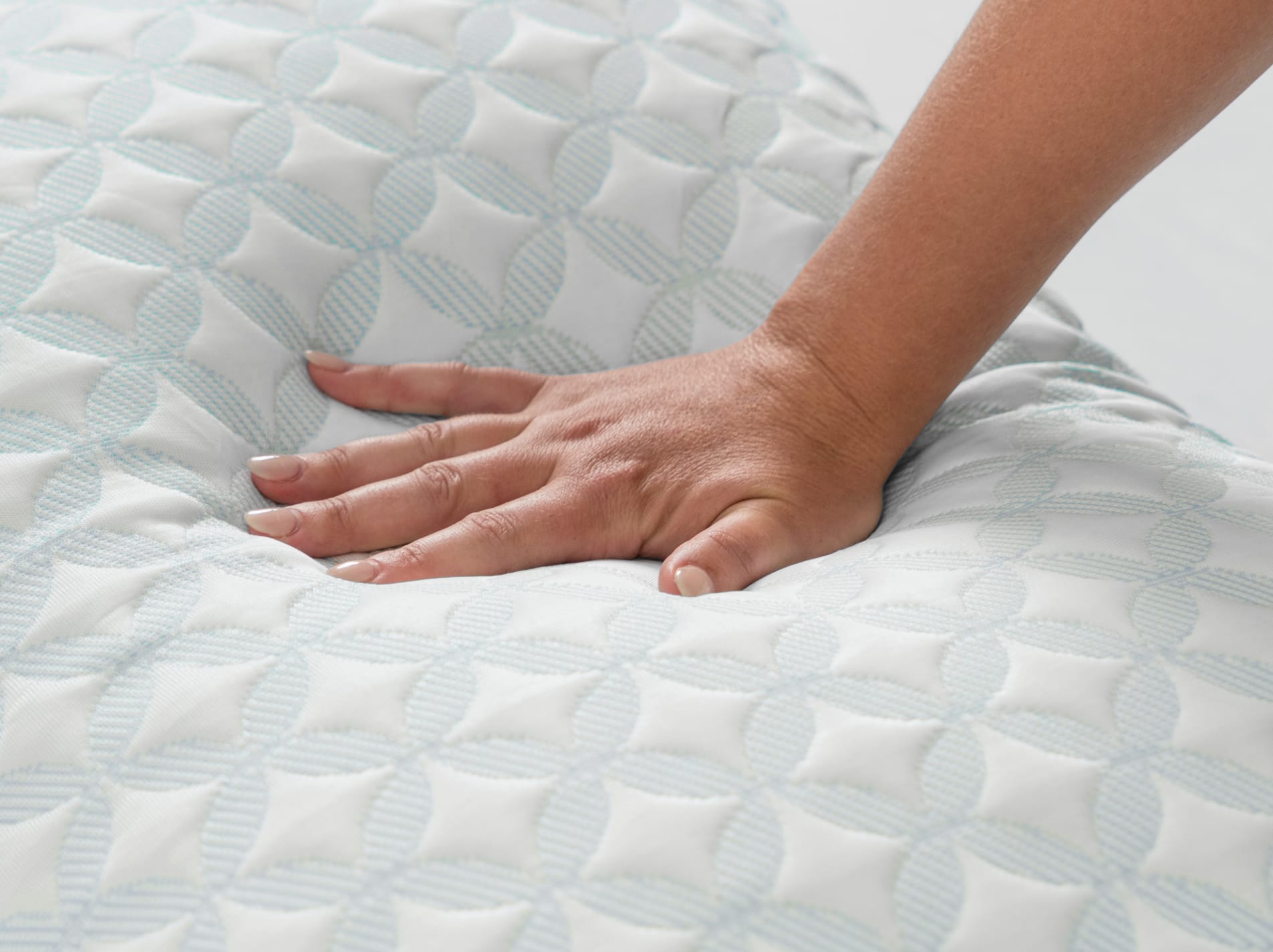 A close-up shot of a hand pressing down on the pillow, demonstrating the soft, conforming feel of the filling.
