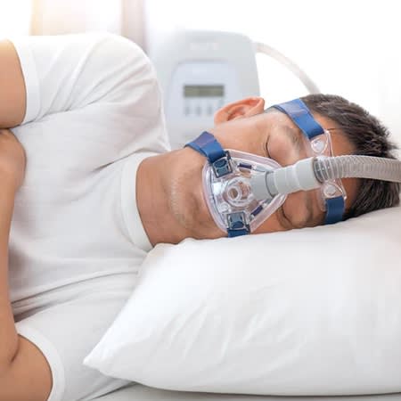 Man sleeping with Sleep Apnea Machine over his face