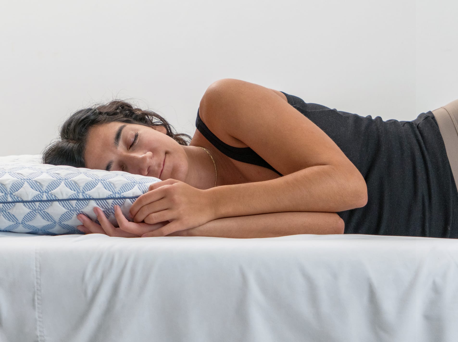 A person is sleeping on their side, with their head resting comfortably on the pillow, which has a blue and white patterned cover.