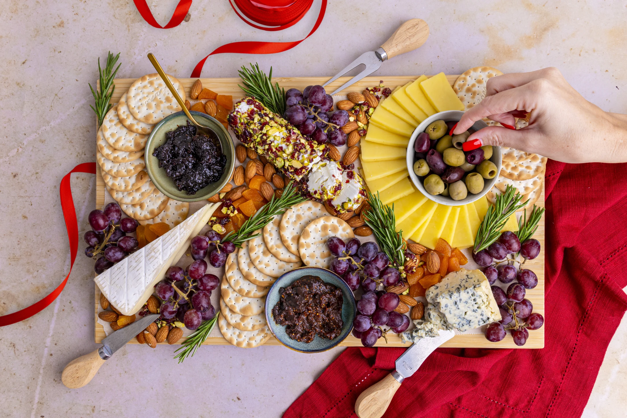 Festive Cheeseboard with Brie, Blue, Goat, and Mature Cheddar; Paired with Grapes, Olives, and Fig Relish.