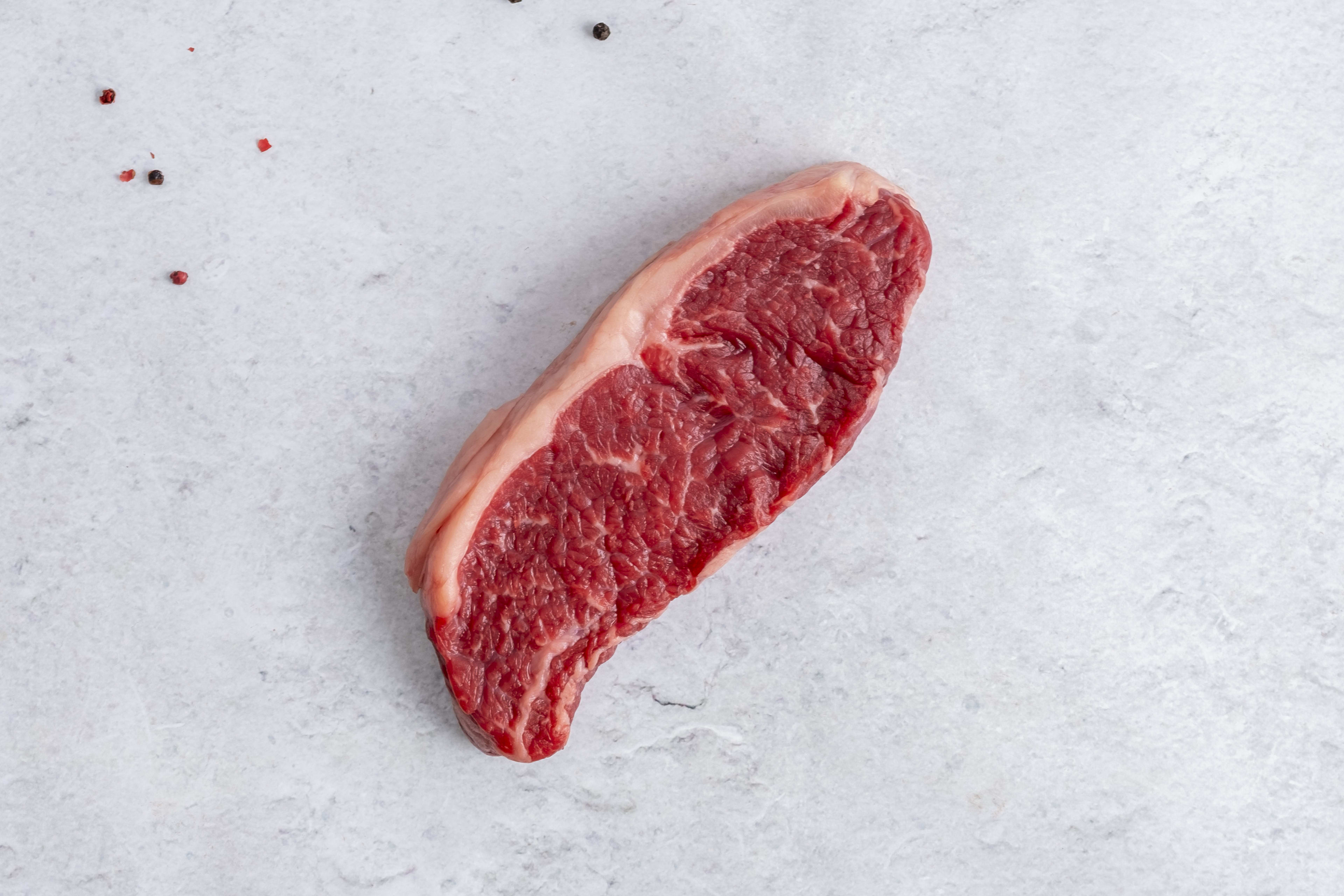 Grass fed sirloin steak, raw, on light marble
