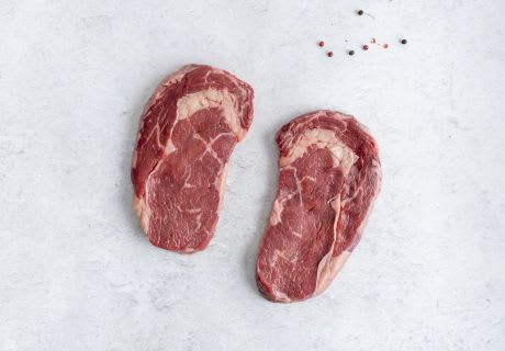 Two New Zealand Angus grain fed ribeye steaks, raw, on light marble