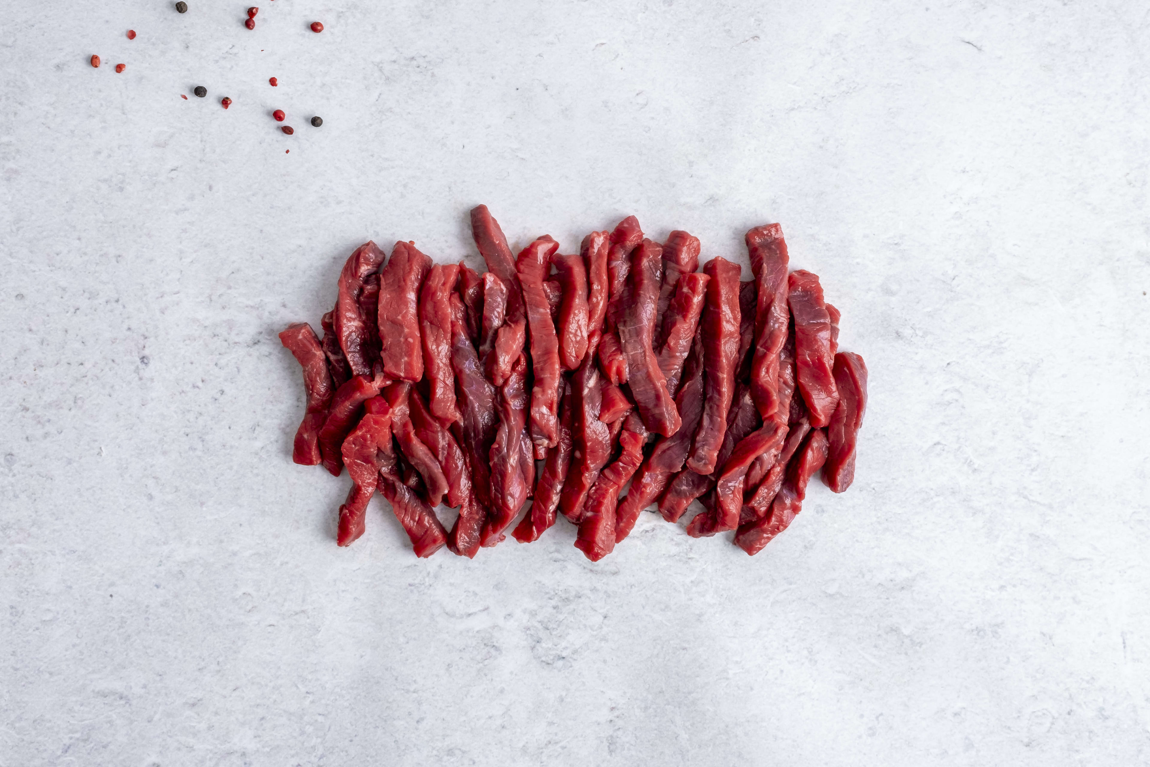 Grass fed beef steak strips, raw, on light marble